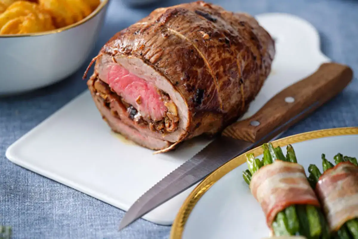 Un rôti de bœuf farci, prêt à être découpé, évoque une délicieuse recette rosbif alsacien. Accompagné de haricots verts enroulés de lard.
