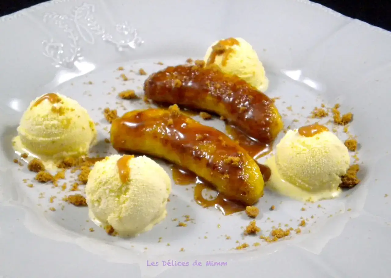 Délicieuse banane grillée à la poêle, nappée de caramel, servie avec des boules de glace à la vanille et des miettes de biscuit.