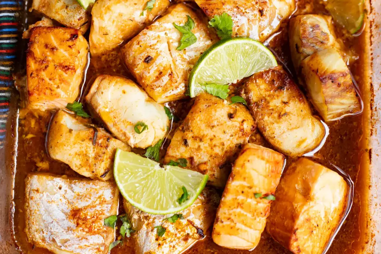 Morceaux de poisson blanc et de saumon, cuits au four avec des épices et des quartiers de citron vert. Un délice qui rappelle un filet de congre au four.