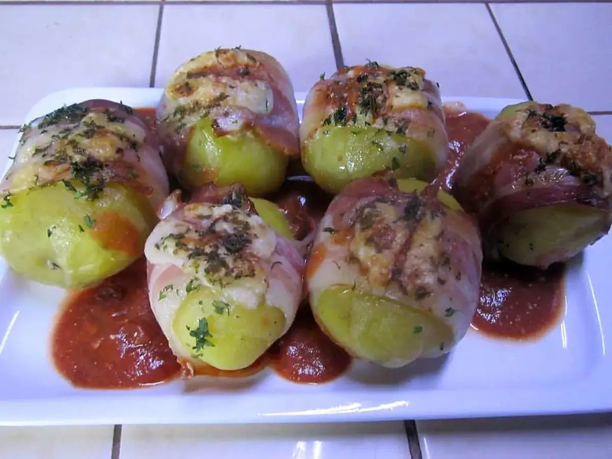 Pommes de terre enroulées de lard, gratinées, servies avec une sauce tomate. Une recette qui rappelle un chapeau chinois coquillage.