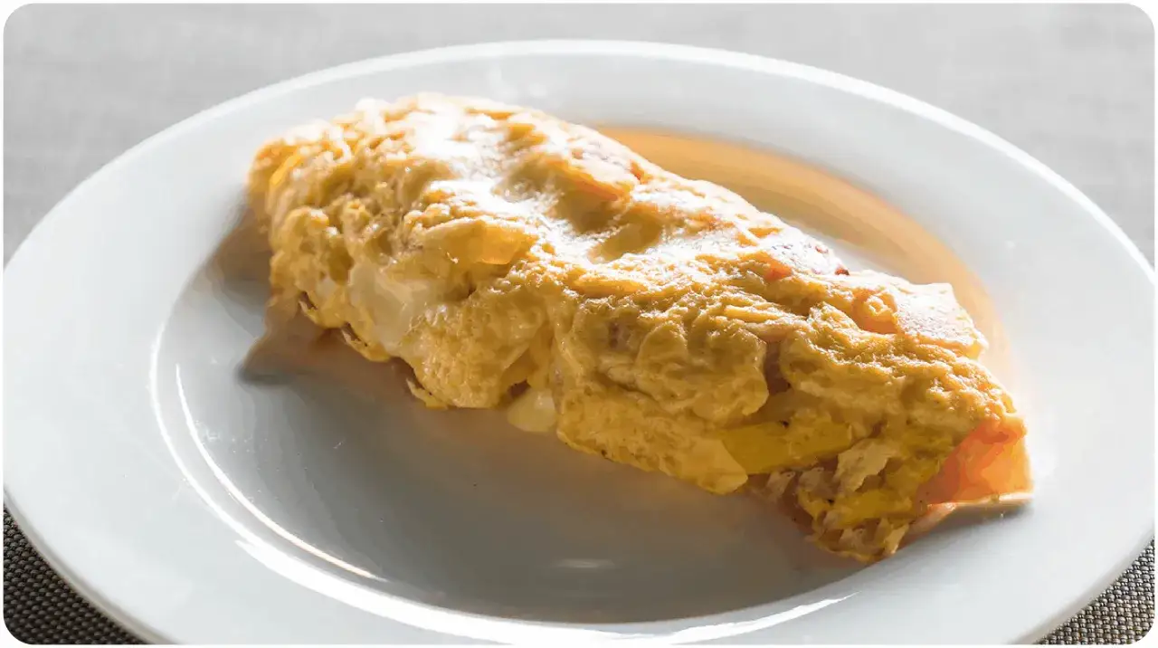 Une savoureuse omelette à l'oseille à l'ancienne, dorée et moelleuse, servie sur une assiette blanche.