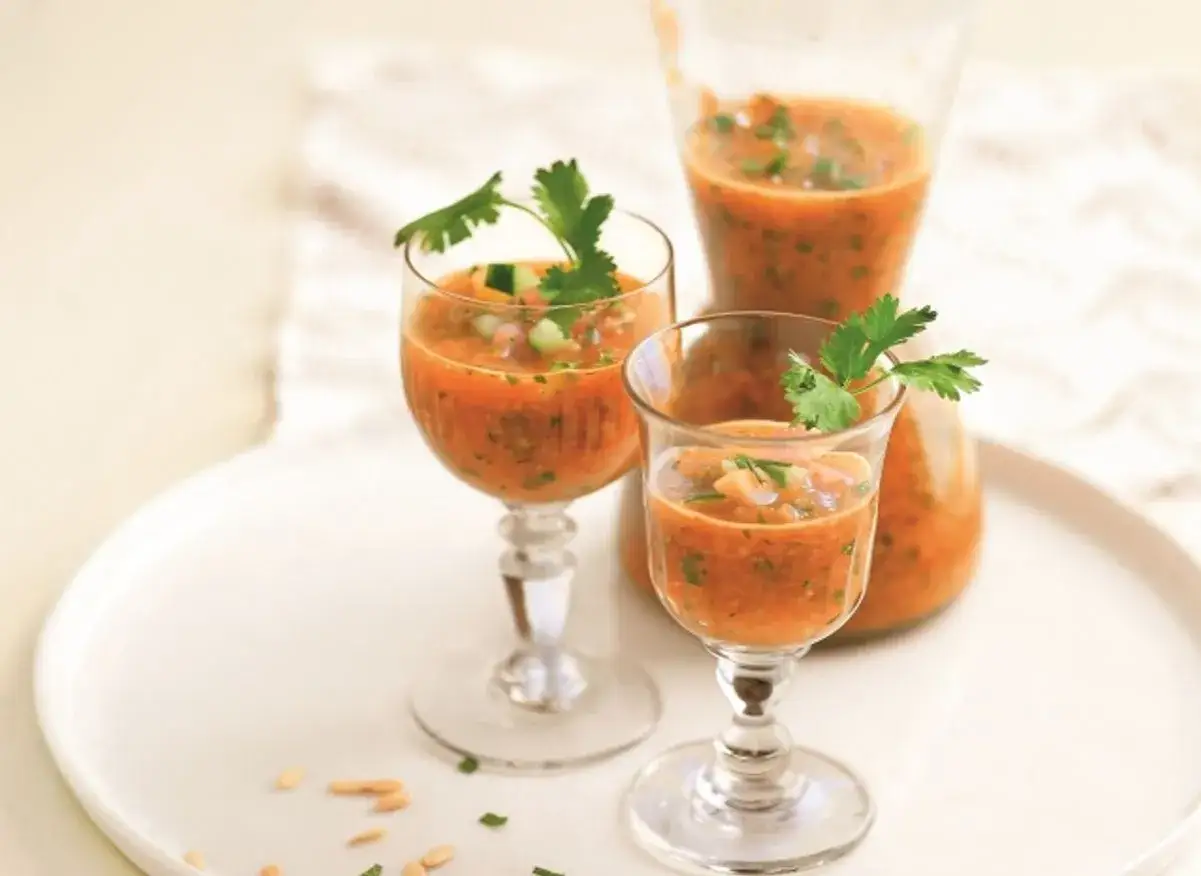 Gaspacho melon concombre rafraîchissant servi dans des verres élégants, garni de coriandre fraîche.