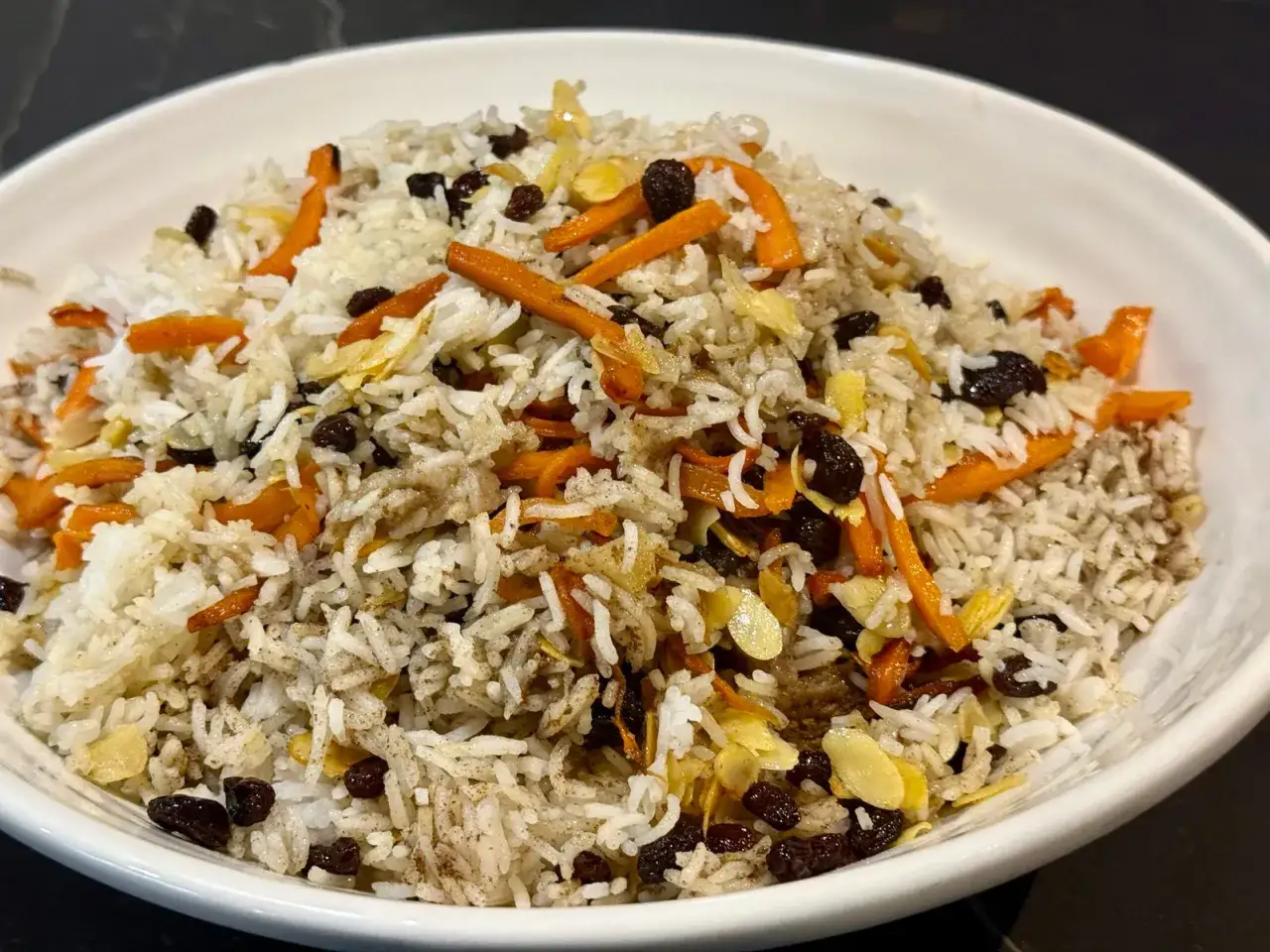 Un plat de riz parfumé, garni de carottes râpées, de raisins secs et d'amandes effilées. Une belle présentation de la recette riz afghan.