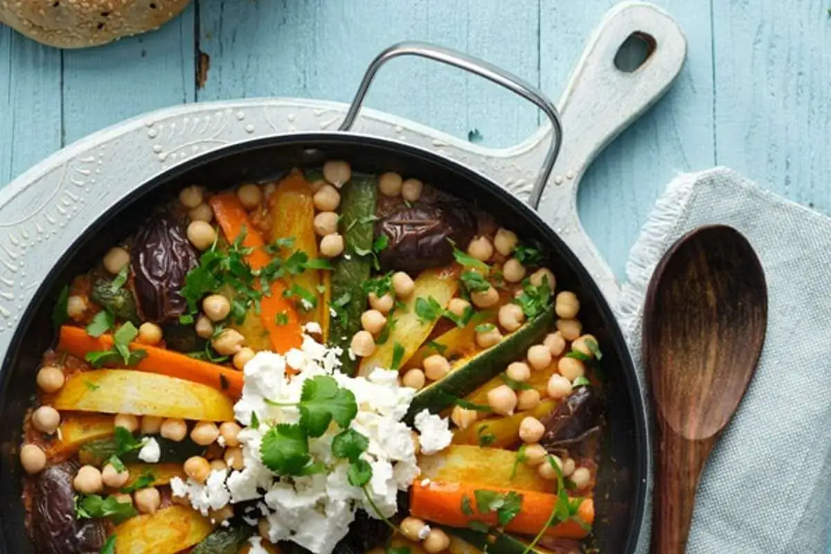 Un savoureux tajine végétarien aux légumes colorés, pois chiches et fromage frais, garni de persil frais.