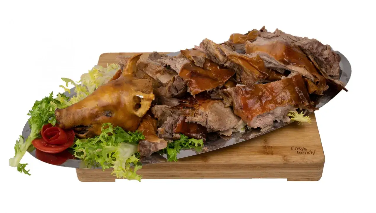Un cochon de lait rôti au barbecue, servi sur un plateau avec de la laitue et une rose en tomate. Le temps de cuisson est parfait pour cette viande tendre.