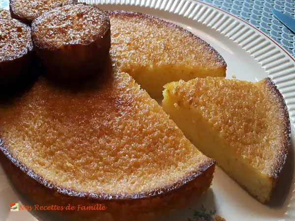 Un délicieux gâteau à l'orange, avec une croûte dorée et une mie moelleuse, servi sur une assiette blanche.