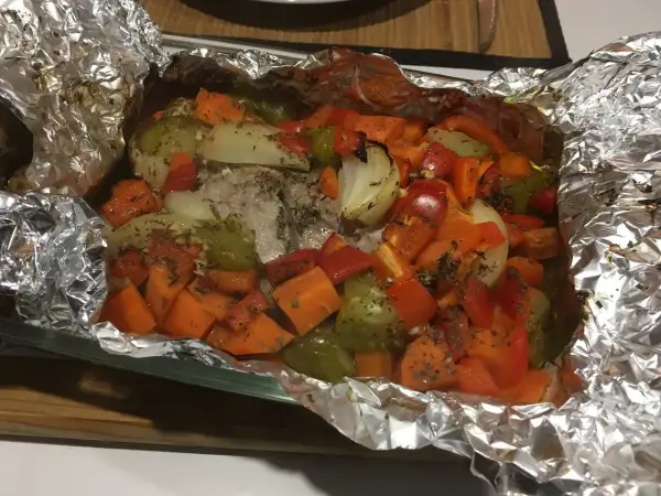 Filet mignon en papillote aluminium, cuit avec des légumes colorés comme des carottes, poivrons et oignons. Un plat savoureux et sain.