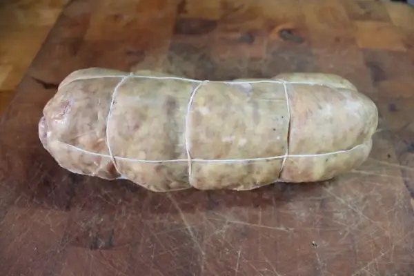 Un sabodet à la vigneronne, charcuterie artisanale ficelée, prête à être cuisinée sur une planche en bois.