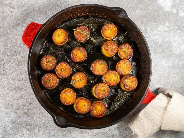 Pommes de terre en sauce brune, dorées et savoureuses, mijotent dans une poêle en fonte avec des herbes aromatiques.