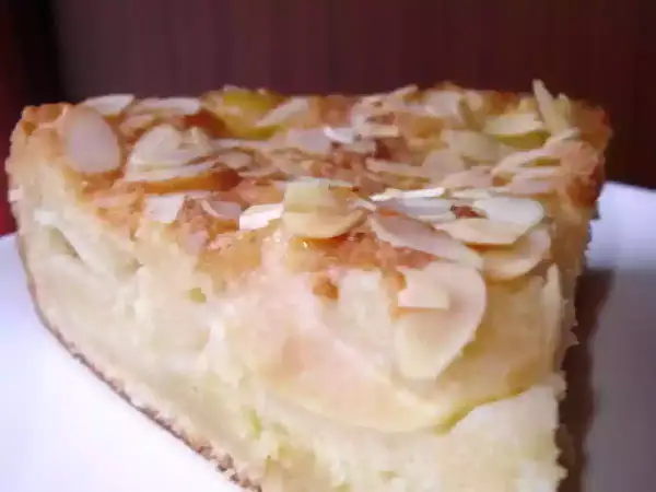 Une part de gâteau d'Ève, aux pommes et amandes effilées, dorée et appétissante.