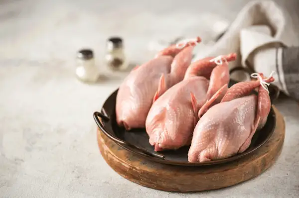 Trois cailles crues, prêtes pour une savoureuse sauce chasseur.