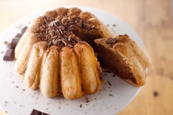 Une délicieuse charlotte malakoff au chocolat, garnie de copeaux de chocolat noir et saupoudrée de cacao.