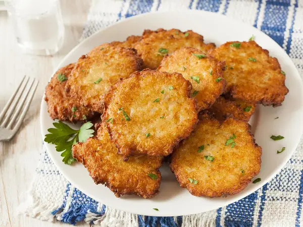 Assiette de beignets de brimbelle dorés, parsemés de persil frais. Un délice croustillant !