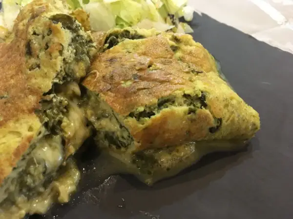 Une savoureuse omelette à l'oseille à l'ancienne, dorée et moelleuse, servie avec une salade verte.