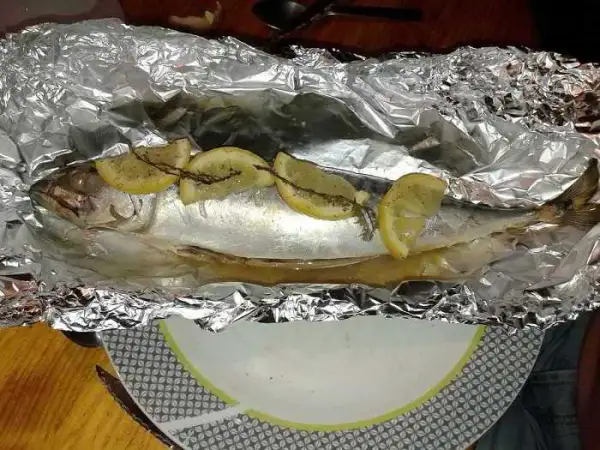 Maquereau entier, prêt à être cuit en papillote au barbecue, garni de rondelles de citron et d'herbes.