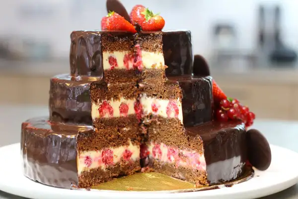 Gâteau à trois étages, chocolaté et garni de framboises, décoré de fraises et de groseilles. Un délice pour les yeux et les papilles, ce gâteau Christine est une œuvre d'art.