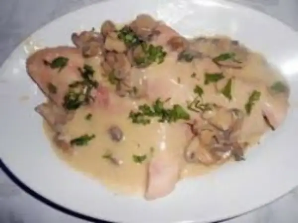 Délicieux jambon braisé au cidre, nappé d'une sauce crémeuse aux champignons et parsemé de persil frais. Un plat réconfortant.