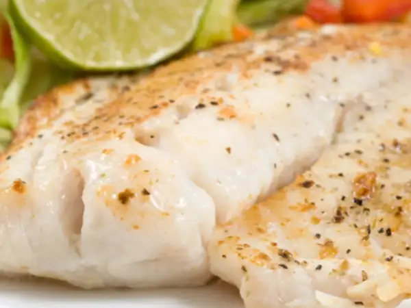 Filet de turbot au four en papillote, tendre et savoureux, servi avec une tranche de citron vert et des légumes croquants.