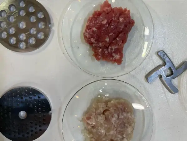 Préparation de viande hachée pour savoir combien de sel et poivre par kg de viande. Disques de hachoir et lames à proximité.