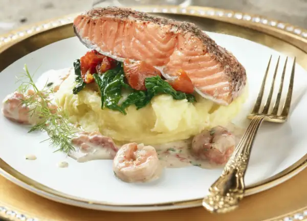 Filet de saumon sur purée, garni d'épinards et tomates, nappé d'une délicieuse sauce crevette. Un plat savoureux.