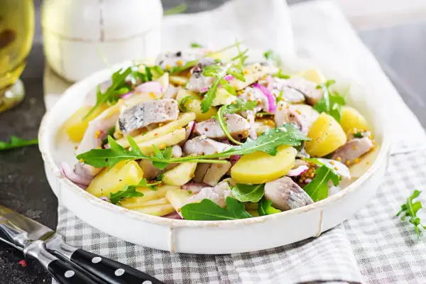 Salade de pommes de terre et hareng frais à la poêle, garnie de roquette et d'oignons rouges. Une recette simple et savoureuse.
