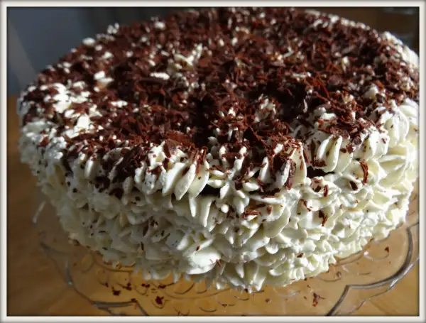 Gâteau noir en chemise de crème fouettée et copeaux de chocolat.