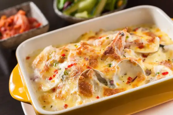 Gratin de coquilles Saint-Jacques, moules, crevettes et champignons, nappé d'une sauce crémeuse et gratiné au fromage. Un délice !