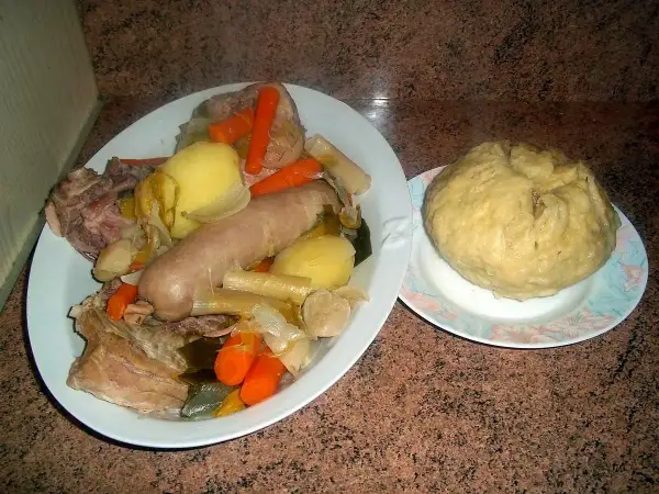 Un plat généreux de la mique origine, avec saucisse, légumes et viande, accompagné d'une mique ronde.