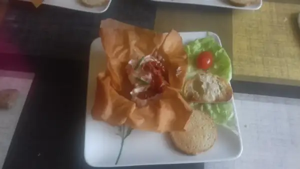 Une délicieuse grolle recette : une coupe de pâte filo garnie de fromage frais, tomates séchées et ciboulette, servie avec des toasts et une feuille de laitue.